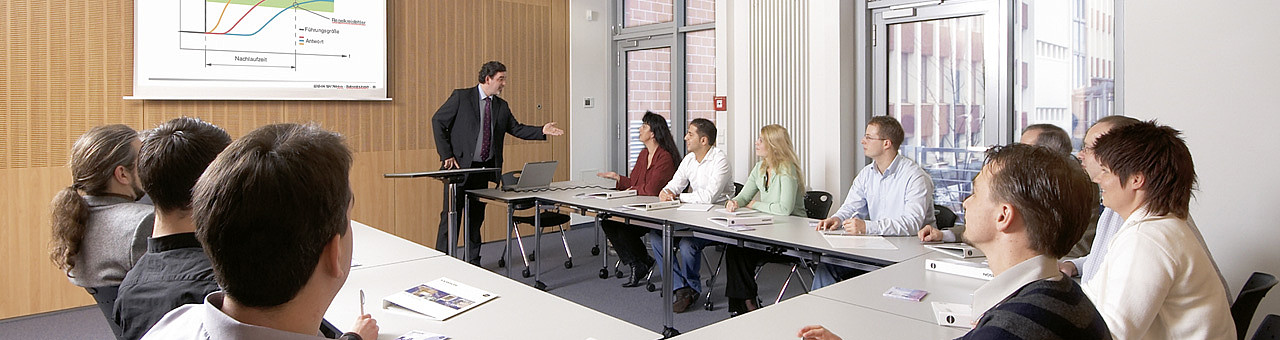 Mann hält Teilnehmern einen Vortrag in einem Konferenzraum